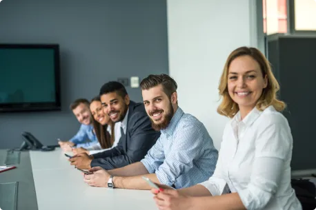 Equipe de profissionais sorrindo em uma mesa de reunião